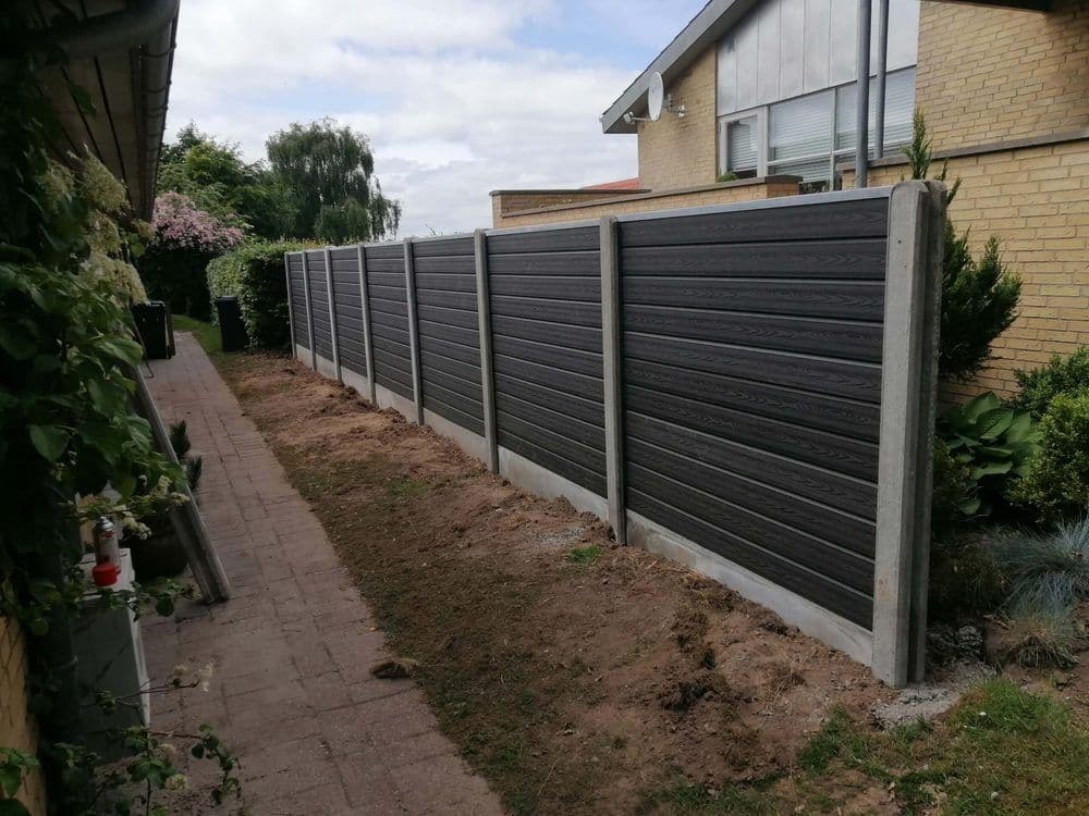 WPC-Sichtschutz in Anthrazit mit Holzstruktur zwischen Betonpfosten entlang eines Gartenwegs
