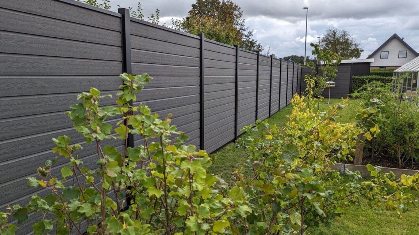 Lange WPC-Sichtschutz-Linie in Anthrazit Holzstruktur auf schwarz pulverbeschichteten Stahlpfosten entlang eines Gartens